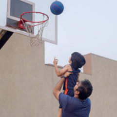 Parent supporting his child to play basketball
