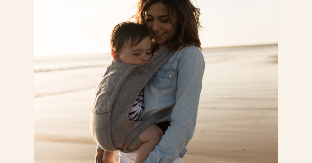 Mother carrying her child in a front sling