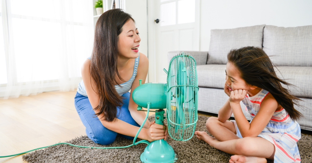 small girl sitting in front of a fan