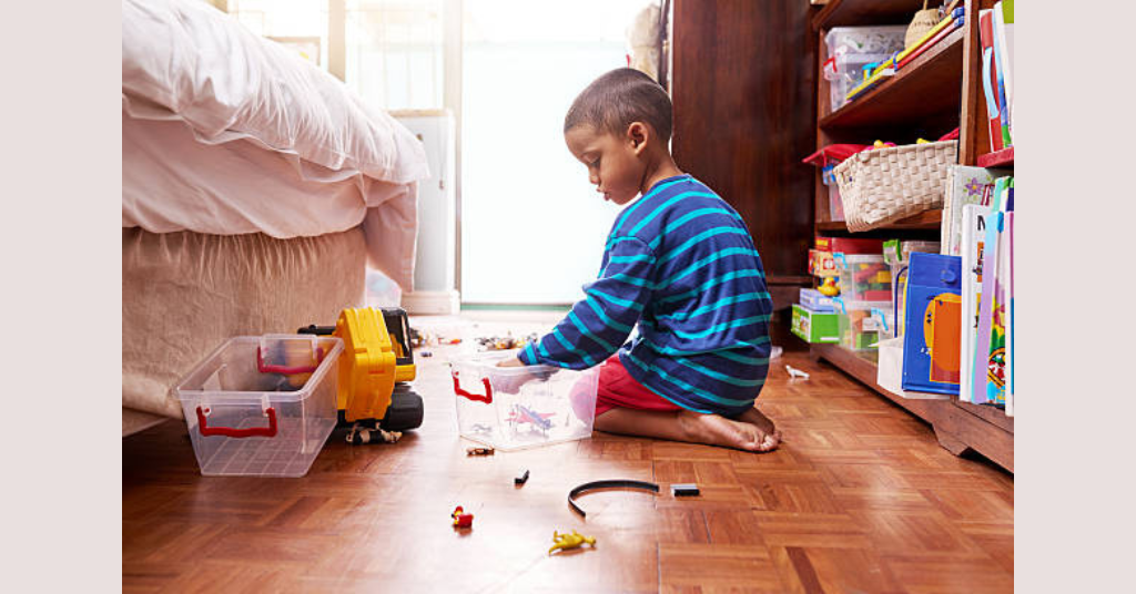 A kid is cleaning his room after the end of play date