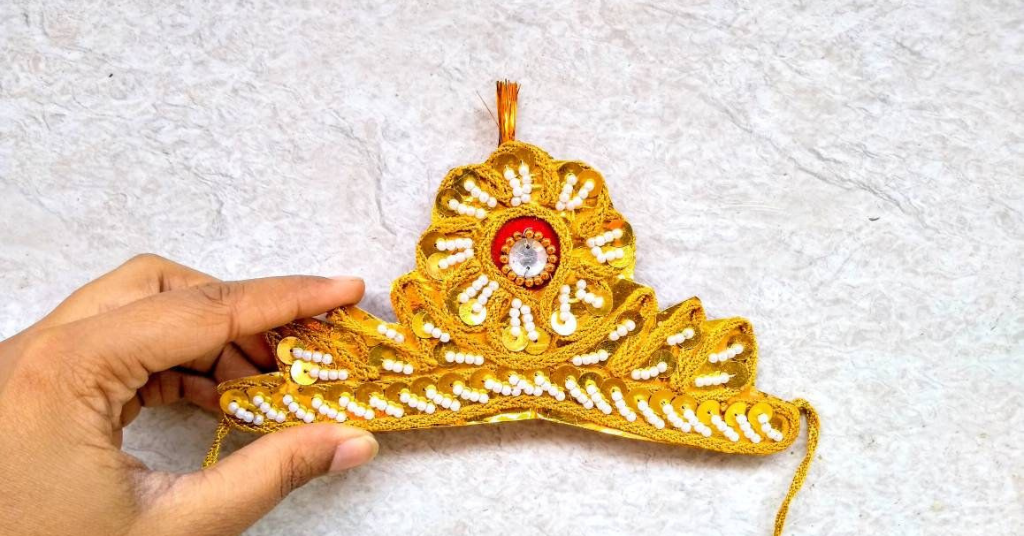 A person holding handmade Lord Krishna's crown